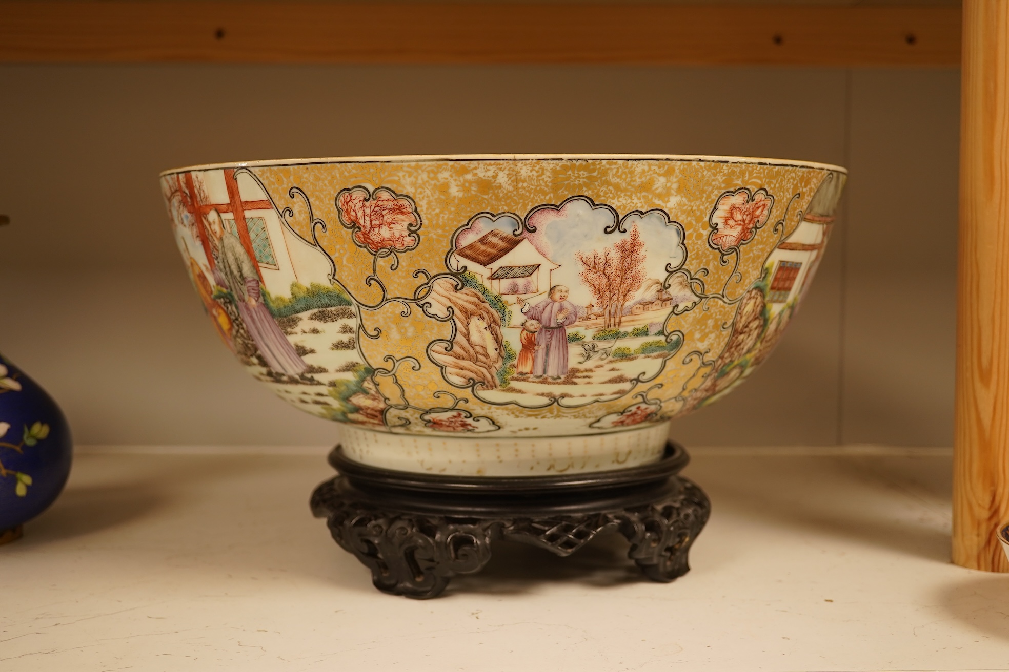 An 18th century Chinese famille rose figural bowl, on wooden stand, 34cm diameter.